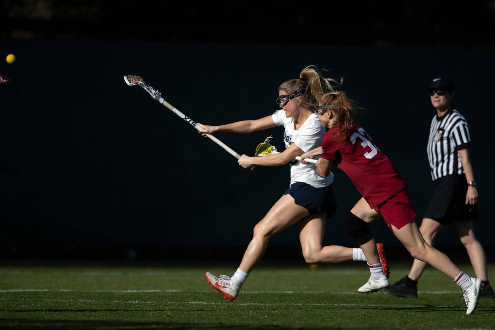 STANFORD, California - FEBRUARY 14:  Virginia Cavaliers midfield Courtlynne Caskin (25) scores a goal past Stanford Cardinal midfield Jacie Lemos (33) during the first half at Cagan Stadium on February 14, 2020 in Stanford, California. The Virginia Cavaliers defeated the Stanford Cardinal 12-11. (Photo by Jason O. Watson)