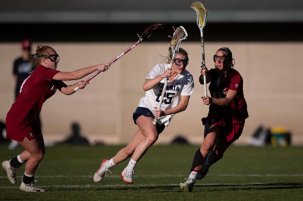 STANFORD, California - FEBRUARY 14:  Virginia Cavaliers midfield Courtlynne Caskin (25) is defended by Stanford Cardinal defense Maggie Bellaschi (11) and midfield Chelsea Trattner (16) during the second half at Cagan Stadium on February 14, 2020 in Stanford, California. The Virginia Cavaliers defeated the Stanford Cardinal 12-11. (Photo by Jason O. Watson)